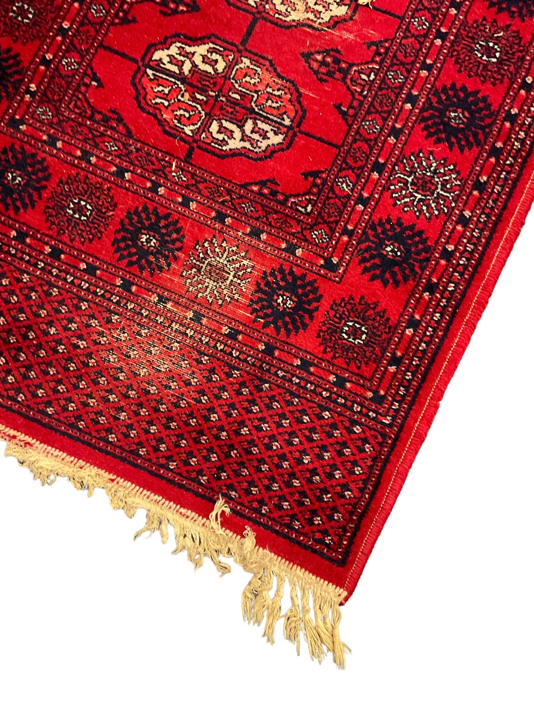 Persian design red ground runner, the field decorated with repeating Boteh motifs, five-band border (277cm x 74cm); Bokhara design red ground rug, decorated with a single row of Gul motifs (272cm x 69cm)