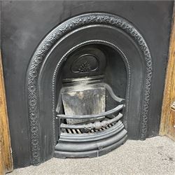 20th century fireplace, oak surround with moulded and scroll carved upright pilasters, with Victorian style cast iron inset and grate, the aperture decorated with flower head motifs