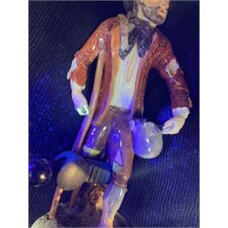 Mid 18th century Furstenberg figure, modelled as a beggar or mendicant with peg leg and bare foot, circa 1755, modelled by Simon Feilner, wearing tattered clothes, one arm supporting an alms pouch, the other holding a crutch, upon a part scrolled base, bearing paper labels beneath including one inscribed 'Sammlung Wilhelm Gumprecht 322', H15cm