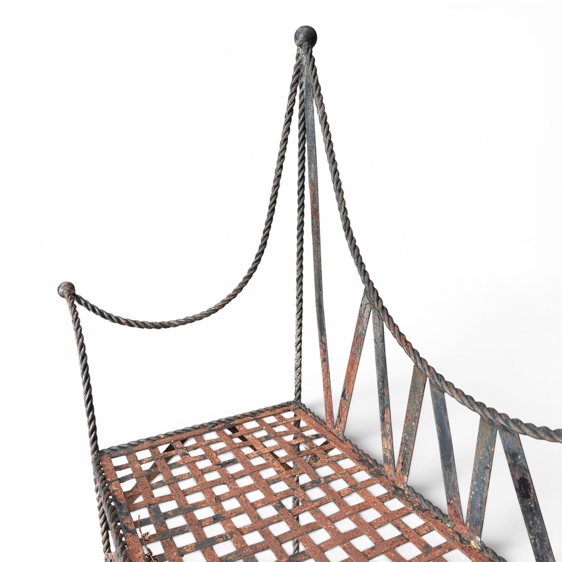 Victorian design wrought iron garden bench, with asymmetrical rope-twist frame, arched back and sides over out-swept arm terminals with ball finials, flanking a lattice seat, in antique black-painted weathered finish