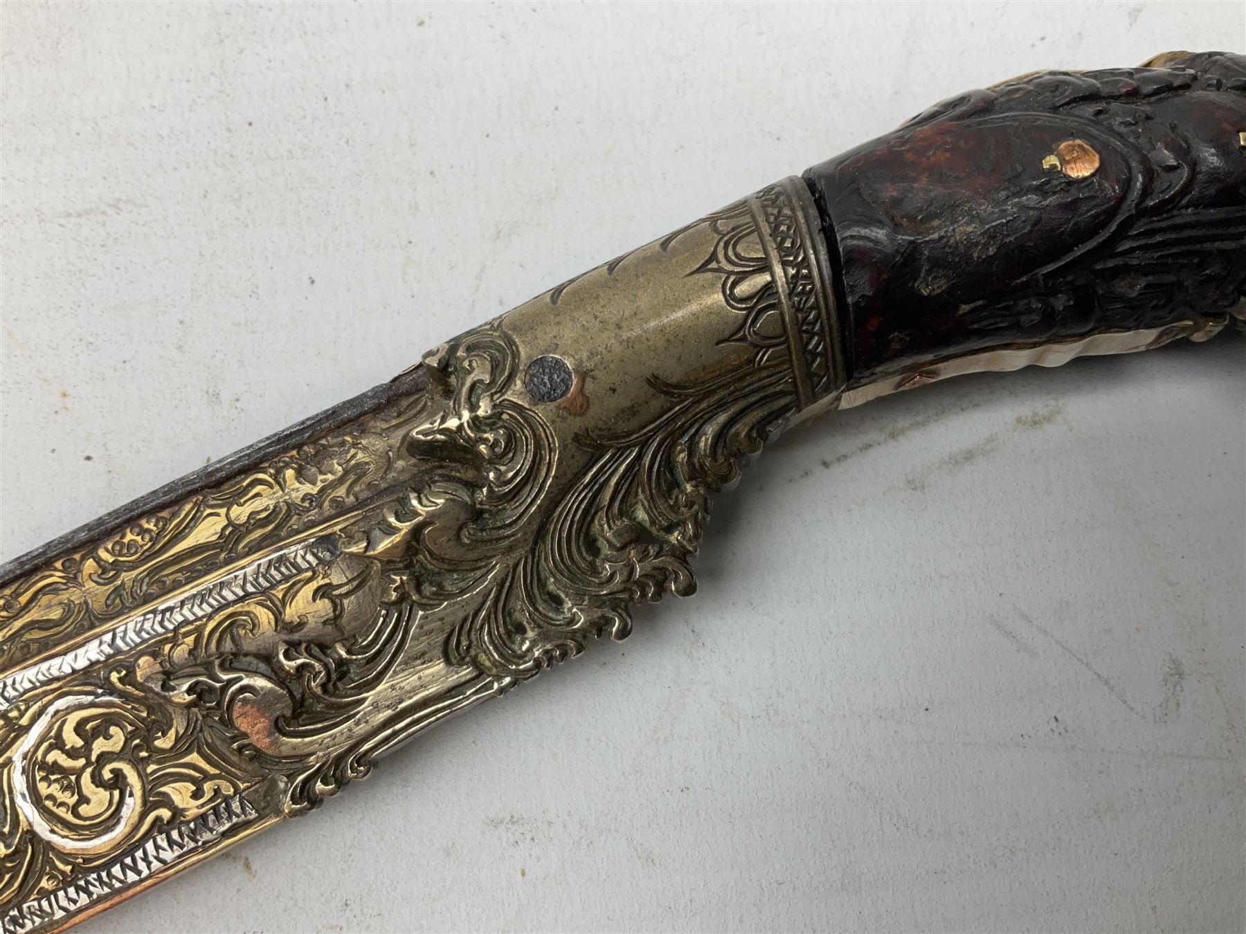 19th century Singhalese knife pia kaetta, the 20cm steel blade inset with yellow and white metal, with metal mounted carved pistol grip, in plain wooden scabbard L33cm overall