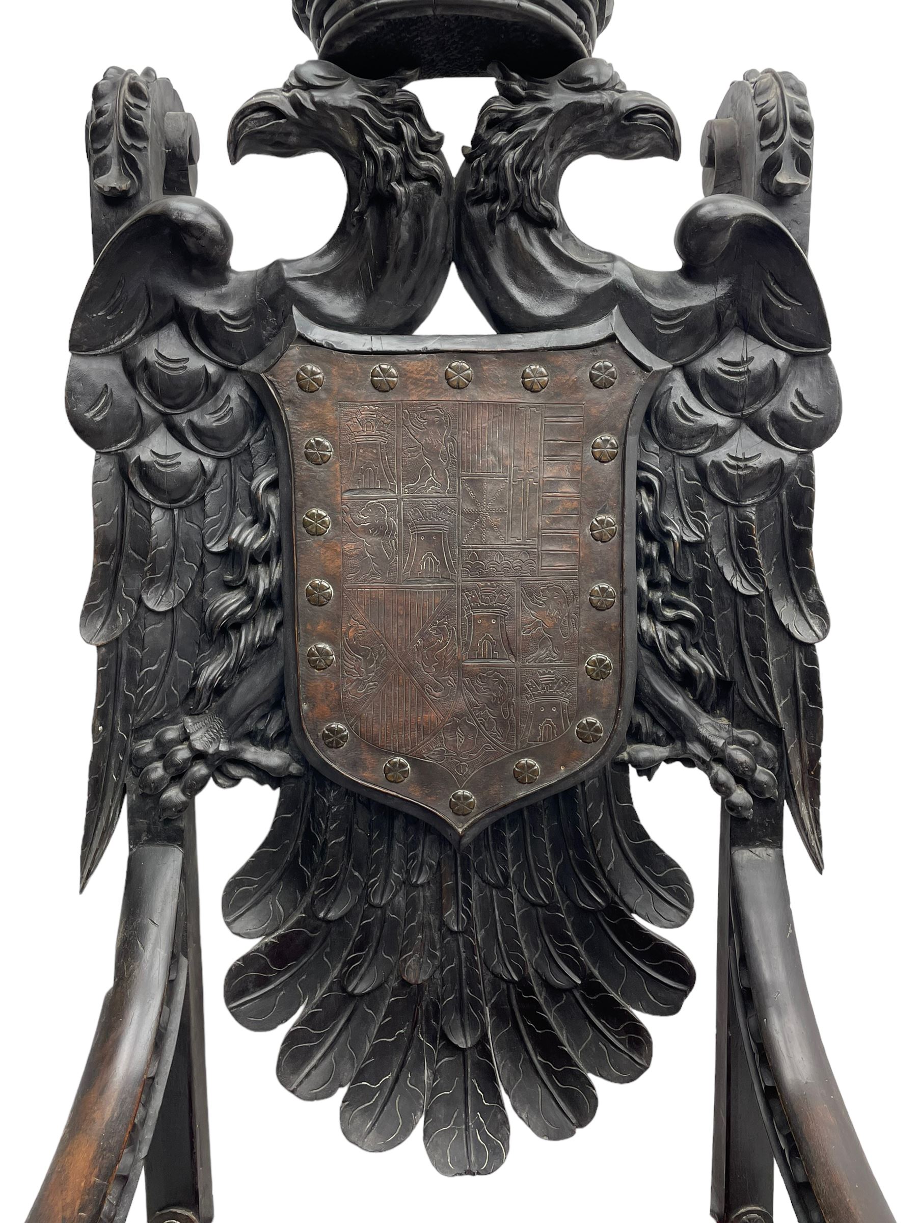 Grand mid-to-late 19th century heavily carved beech framed throne chair, the crown pediment carved with flower heads and cross finial, scroll and acanthus carved upright supports with twin perching griffin back enclosing etched leather work heraldic shield with castle and lion motifs over splayed feathers, flower head carved down sweeping arms with grotesque carved terminals, the seat rails carved with further flower heads on moulded supports with oversized ball and claw carved feet

Provenance: A very similar chair was used in the filming of Stanley Kubrick's 'Eyes Wide Shut' (1999)
