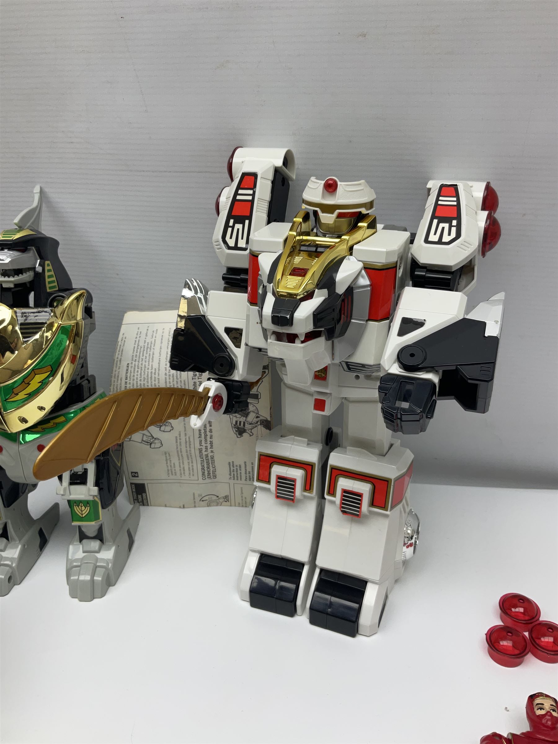 Collection of early 90s Mighty Morphin’ Power Rangers Zords, figures and accessories. Titanus the Carrier Zord, marked Bandai 1991; Green Dragonzord, incomplete; 1994 White Tigerzord with original instruction manual; 1993 Triceratops Dinozord, Mastodon Dinozord and Sabertooth Tiger Dinozord, Pterodactyl Dinozord, missing guns; with 1993 Power Morpher and original Power Coins, with further related figures, accessories and weapons