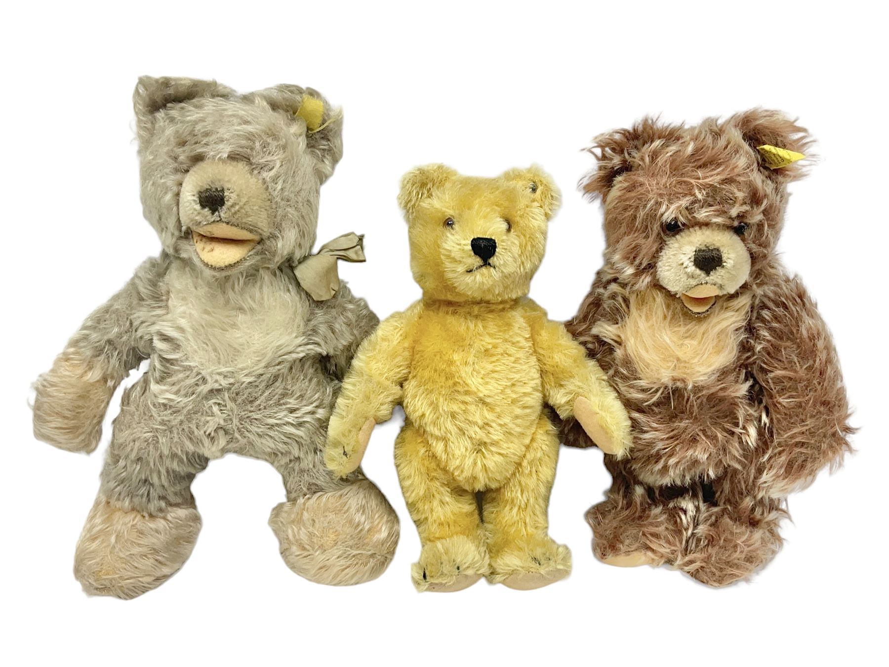 Steiff teddy bear with golden plush body, revolving head, applied eyes, vertically stitched nose and mouth and jointed limbs; button to left ear H26cm; and two other Steiff teddy bears, each with open mouth and button with tag to left ear (3)
