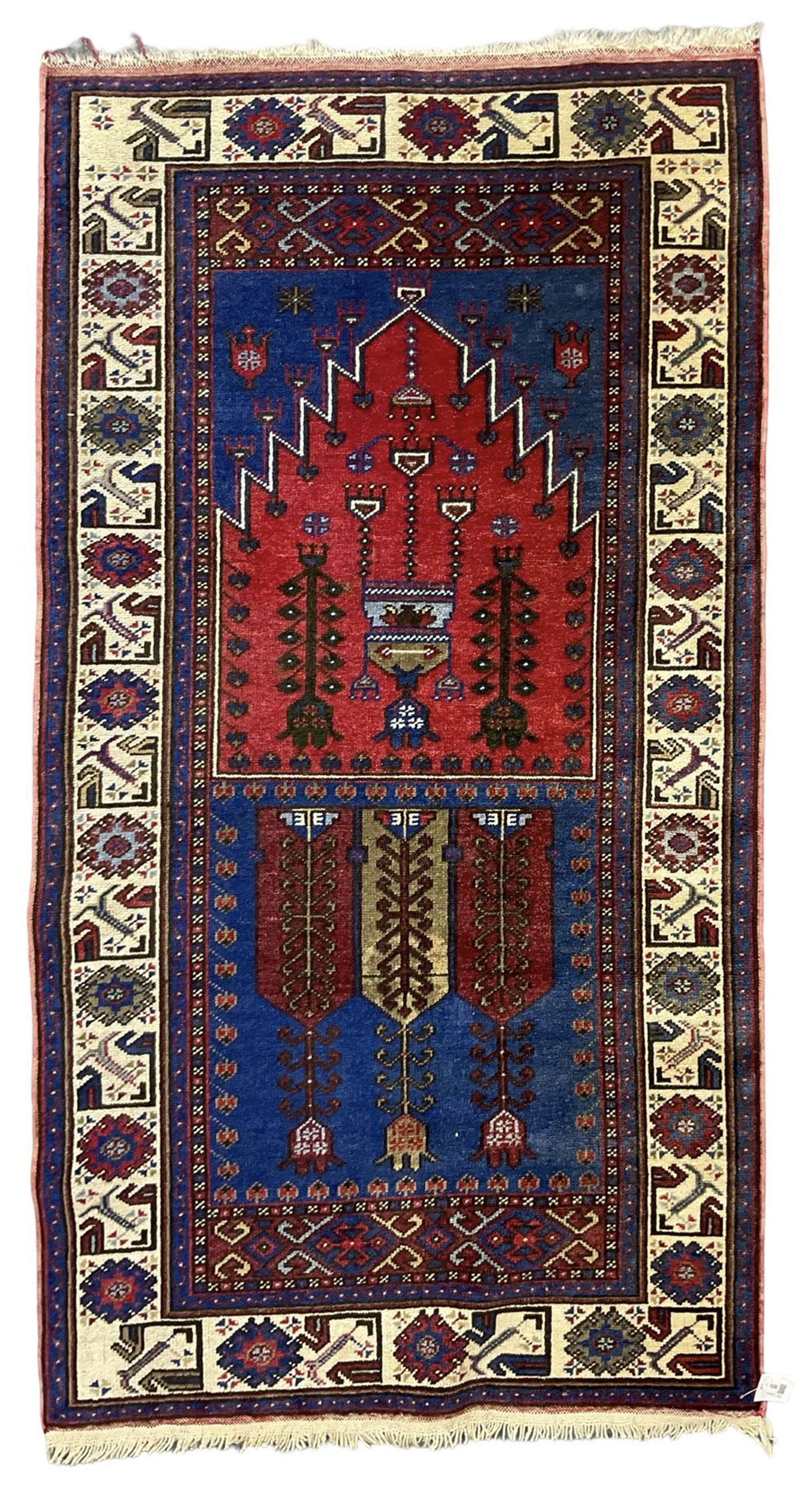 Turkish Yuruk indigo ground rug, the field decorated with geometric architectural designs, the guarded ivory border with repeating stylised plant motifs