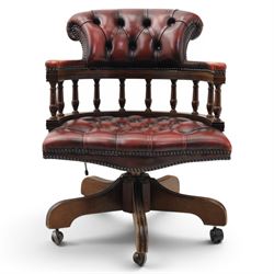 Captains swivel desk chair upholstered in oxblood leather, buttoned back and seat, shaped arm bow raised on turned spindles, five spoke base raised on castors