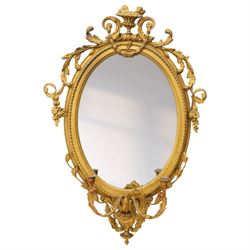 Late 19th century Louis XVI style giltwood and gesso girandole oval wall mirror, the oval frame surmounted with stylized urn finial and ribbon-tied garlands, laurel swags and rosettes, egg and dart decorated inner moulding and linked acorn outer moulding, flanked by intertwined foliate decorated candle branches 