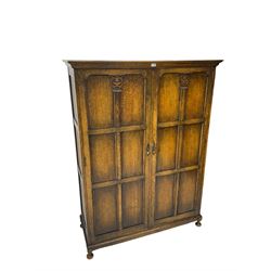 Early to mid-20th century oak double wardrobe, projecting cornice over two panelled doors with Corinthian column decoration, on pad feet