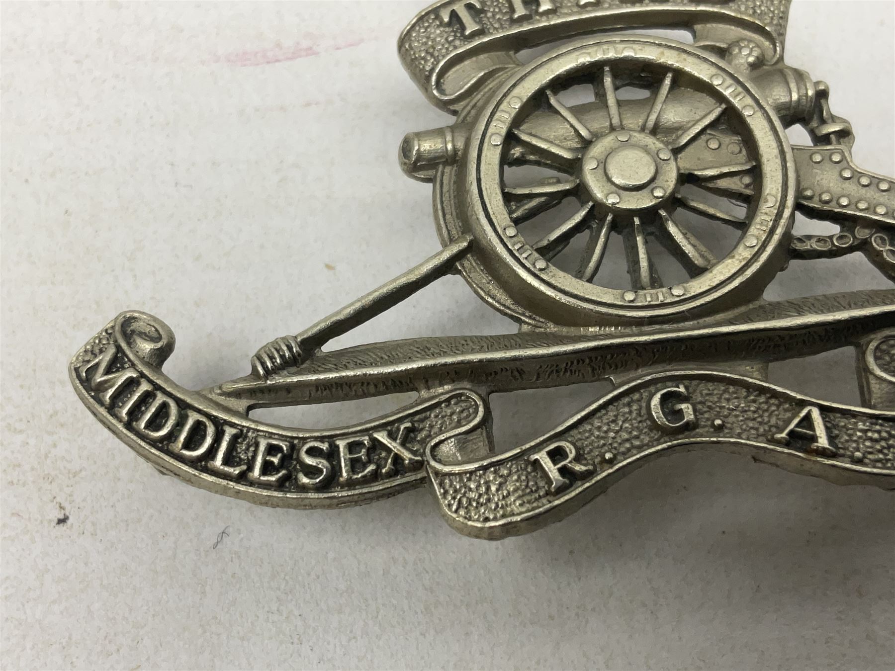 Third Middlesex Royal Garrison Artillery Volunteers Cap Badge, white meta Royal Artillery cap badge with “THIRD” to the top scroll and lower three part scroll “MIDDLESEX – R.G.A. – VOLUNTEERS”. Three lug fittings to the reverse.