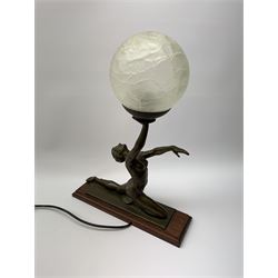 A bronzed Art Deco style table lamp in the form of a dancer, supporting a globular glass shade, overall H45.5cm.