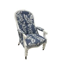 Late 19th century white painted armchair, spoon back with scrolled arm terminals and turned supports with castors, upholstered in button-back blue and white patterned fabric with sprung seat