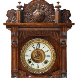 Late 19th century-8-day American Ansonia mantle clock, in a carved oak case with an enamel dial and gilt dial bezel, twin train spring driven movement striking the hours on a coiled gong. With pendulum.
