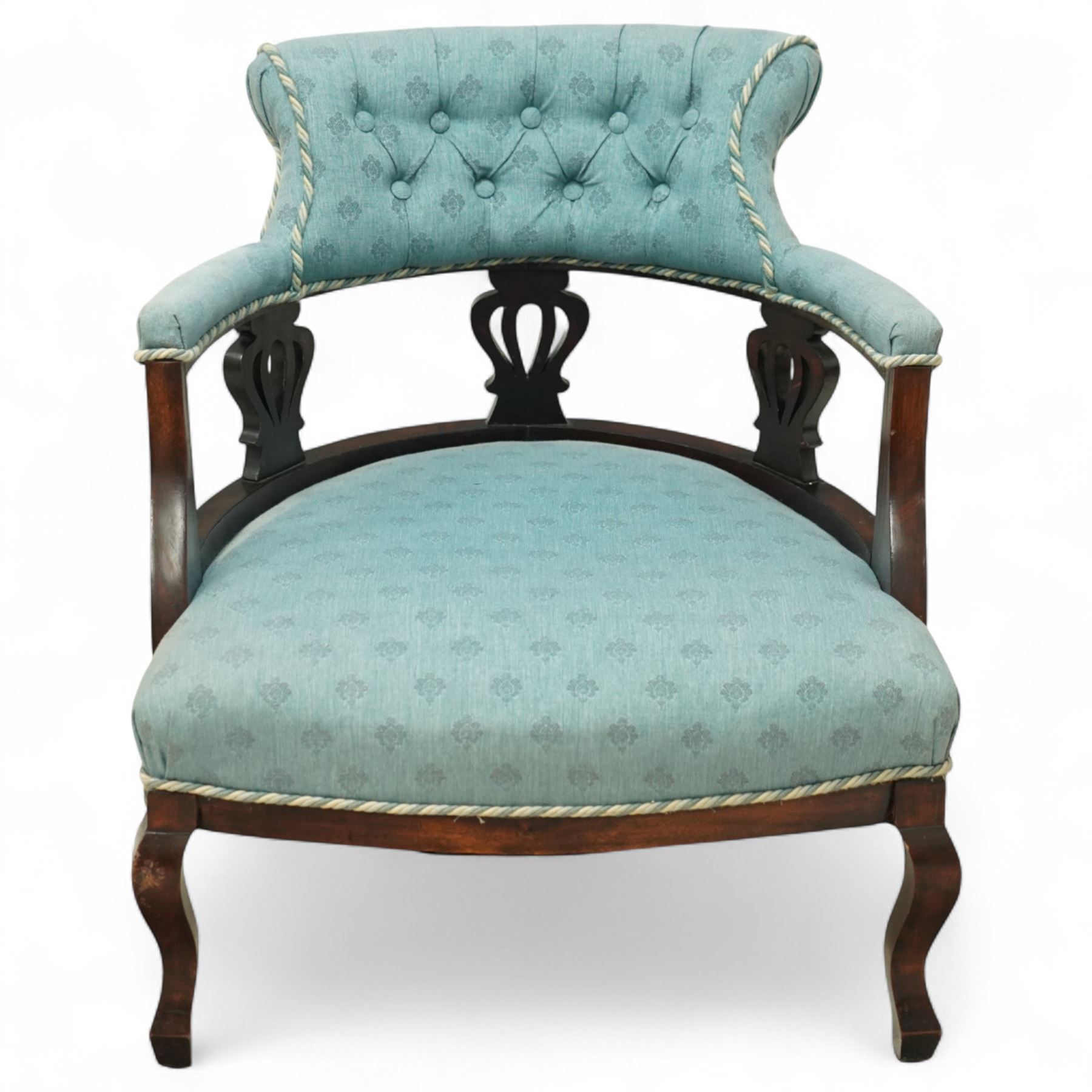 Late Victorian mahogany upholstered tub chair, curved button-back with rope-edge trim over open shaped arms and pierced splat supports, rounded seat upholstered in patterned blue fabric, raised on cabriole front supports