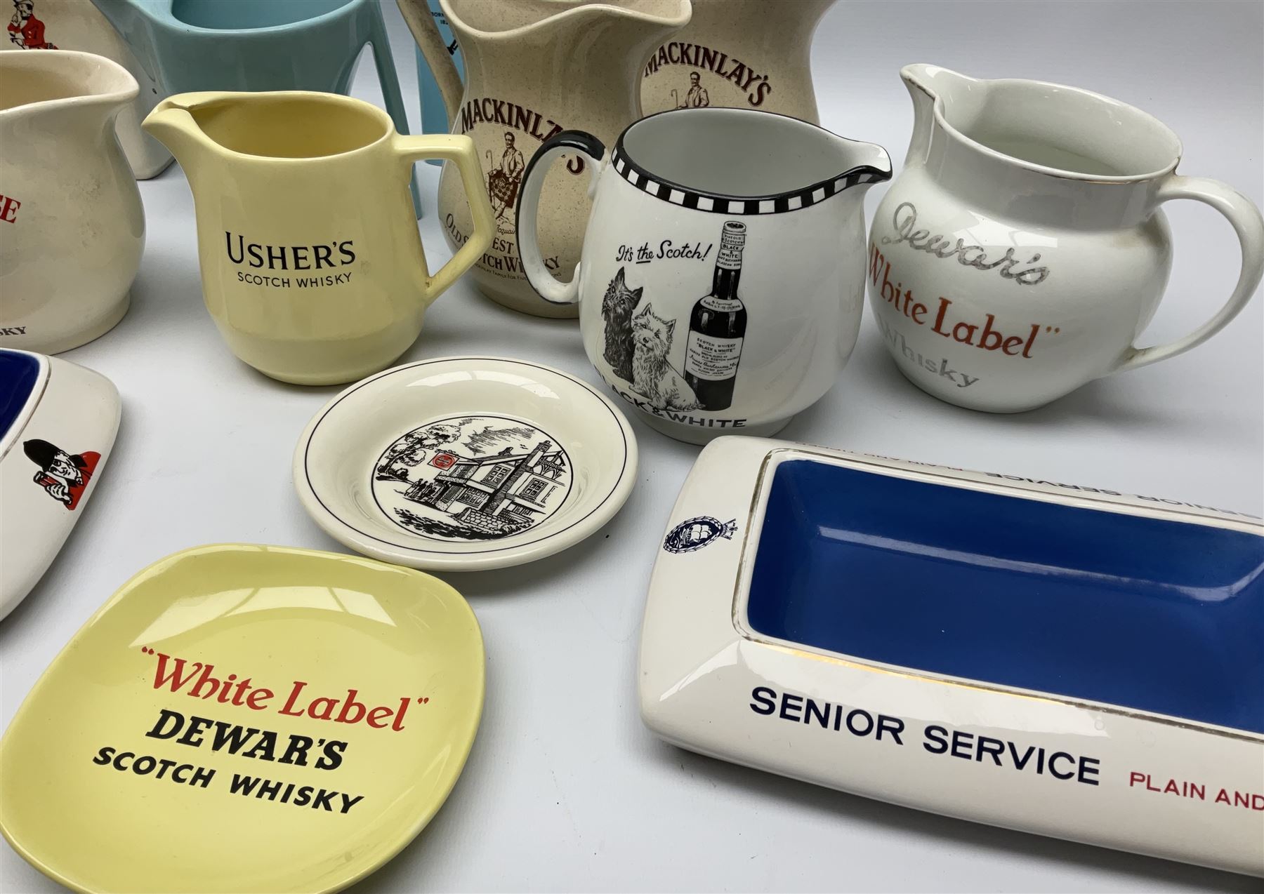 Collection of ceramic pub jugs and ashtrays, including Senior Service ashtray, Bell's old scotch whiskey ashtray,Arthur Bell & sons jug, Beefeater gin jug, two Black and White scotch whiskey jugs, etc    