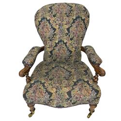 Victorian walnut framed open armchair, scrolled arm terminals over spiral turned arm supports, upholstered in foliate patterned fabric with sprung seat, on turned supports and brass castors (W65cm H92cm); and Victorian mahogany nursing chair with lobe carved supports (W60cm H92cm)
