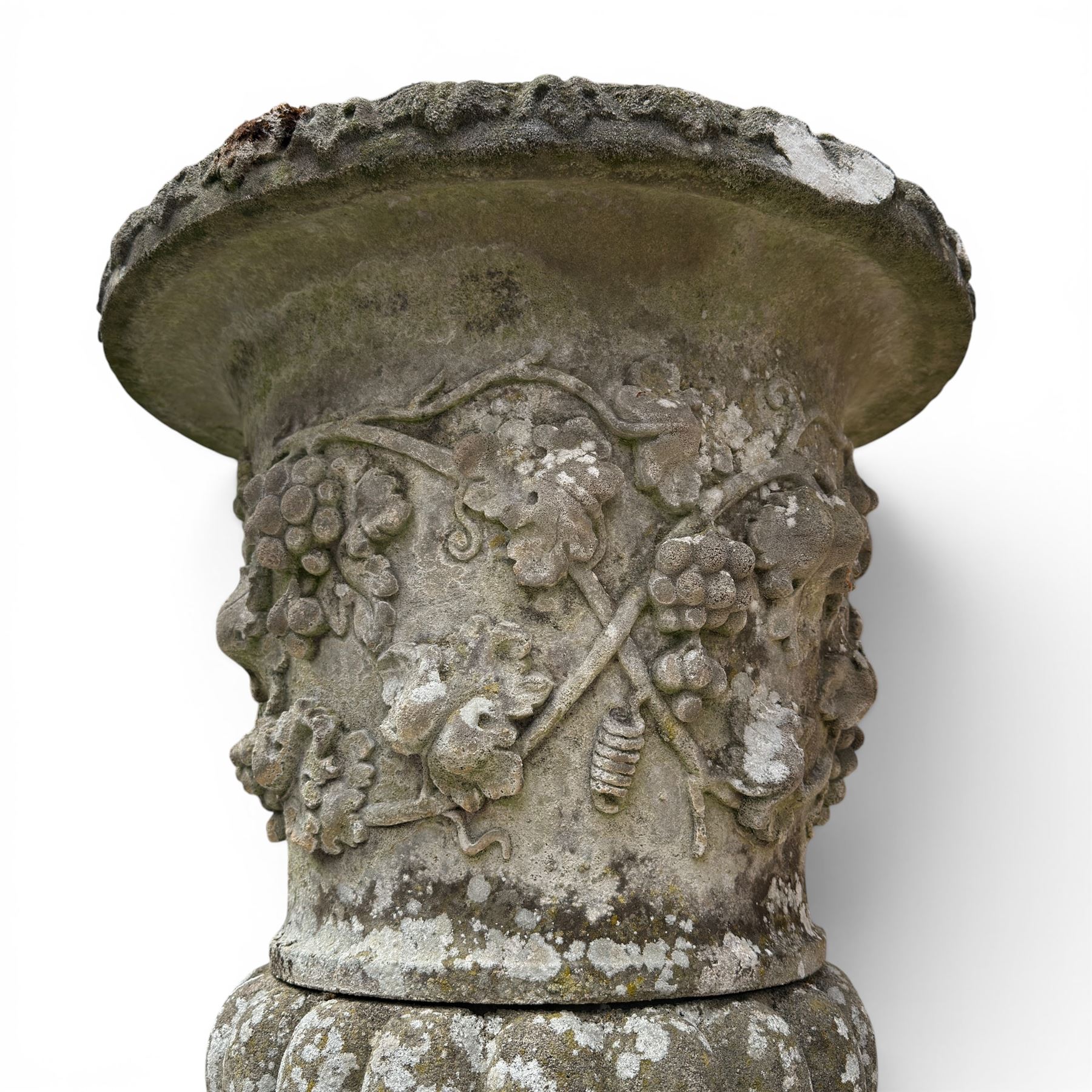 Pair of quality antique weathered three-piece composite stone garden urns, the flared rim moulded with repeating acanthus leaves, over a deep-relief campana body decorated with fruiting grapevines and ivy leaves, the gadrooned underbelly over a turned socle and square base