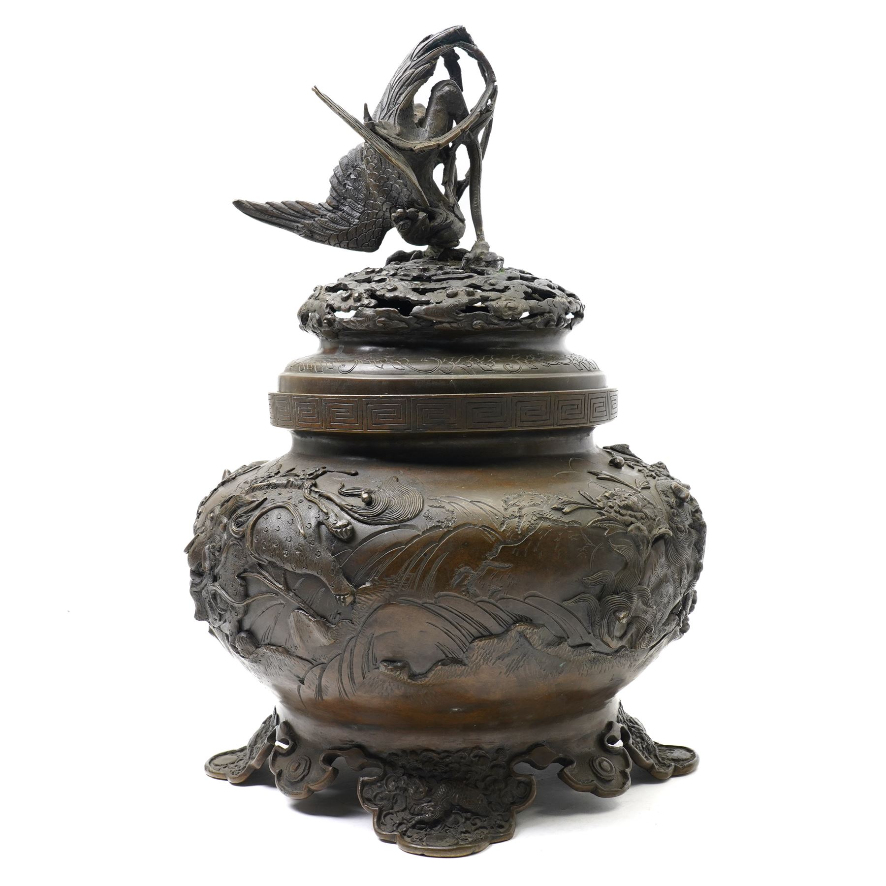 Japanese Meiji period bronze Koro, c.1870-1880, of squat baluster form, each foot with elaborate floral and mythical creature decoration, the body depicting two lions in chase, the rim with Greek key border, the pierced cover with eagle finial, Yoshida foundry mark to base, H50cm