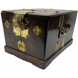 Chinese brass bound hardwood travelling vanity box of oblong form with side carrying handles, the hinged top opening to reveal a hinged toilet mirror above a pair of doors enclosing various drawers and compartments on a stepped base with carved and moulded decoration W28cm H23cm D38cm