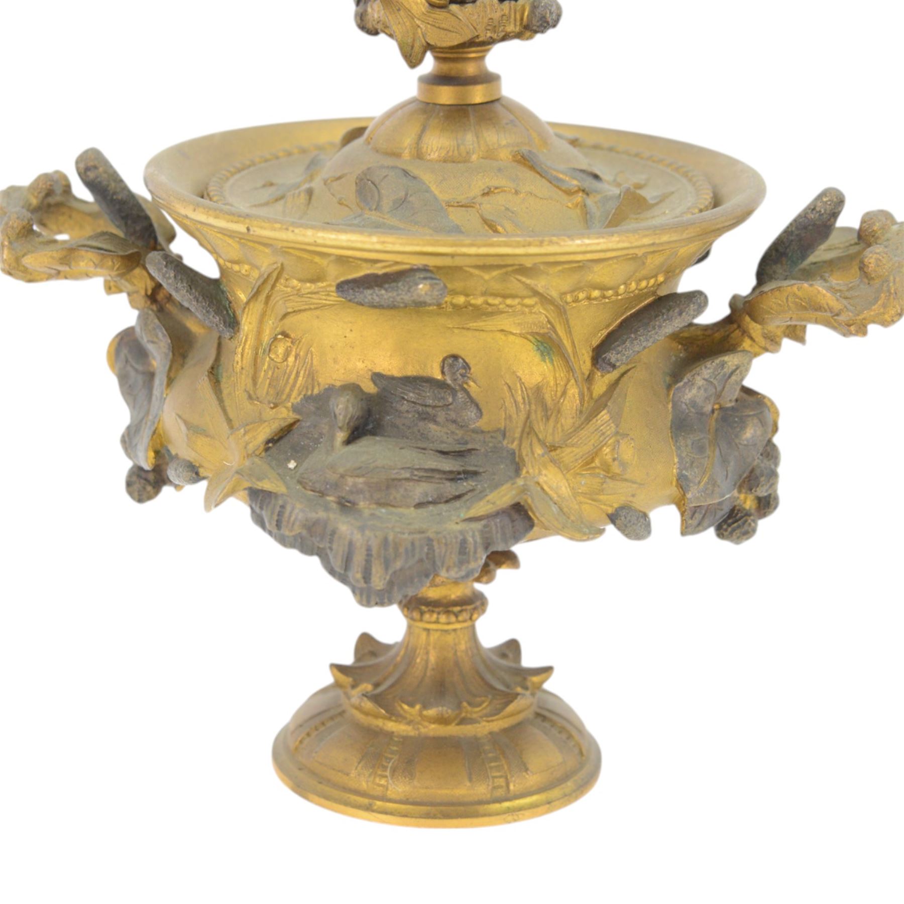 19th century gilt bronze twin handled urn, the removable cover with foliate decoration and finial modelled with a putti and swan, the body decorated in relief with swans and reeds, upon a circular foot, H19cm