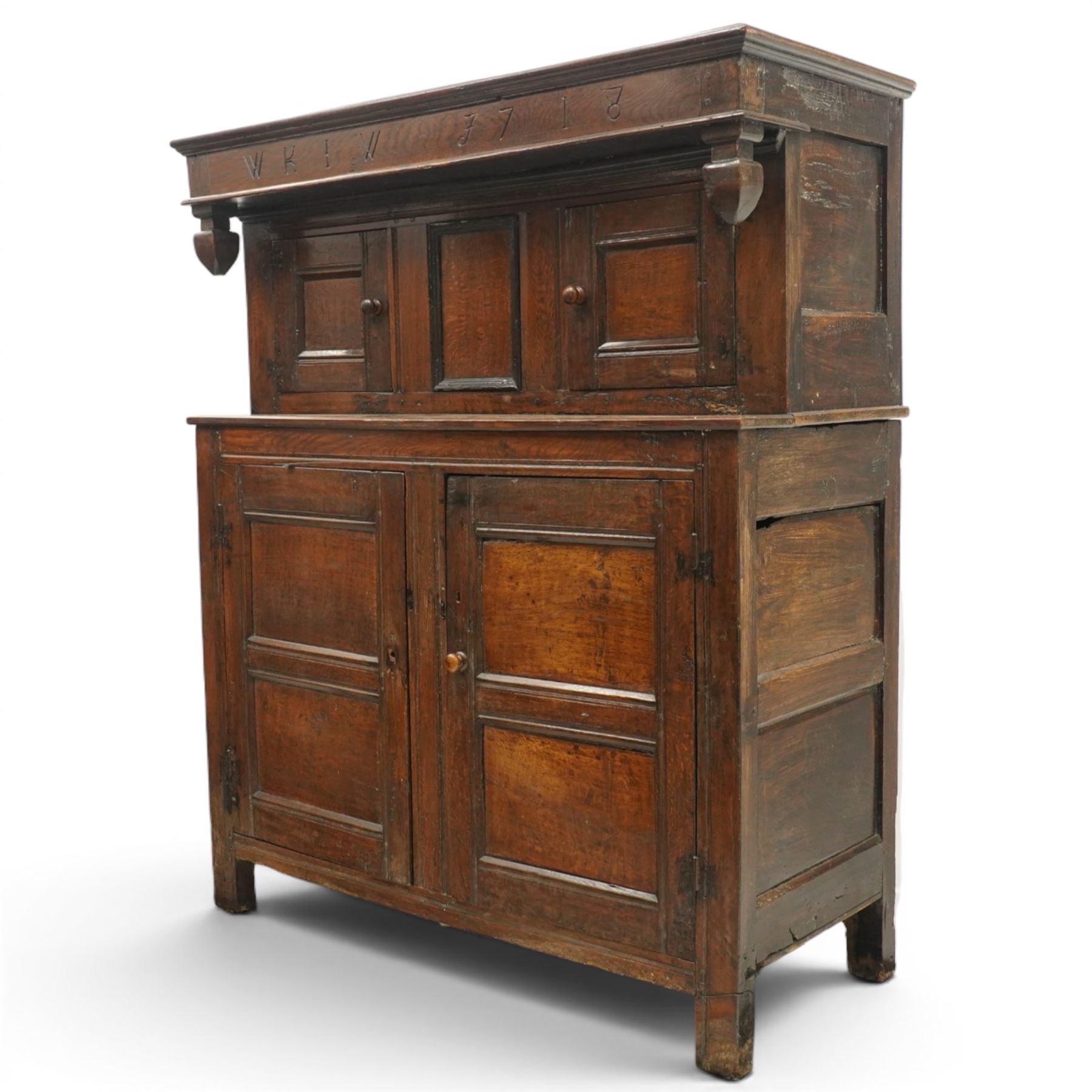 Early 18th century oak court cupboard, the projecting cornice carved with initials 'WKIW' and dated 1718 with turned terminals, fitted with two recessed panelled cupboard doors, large cupboard to base, raised on stile supports