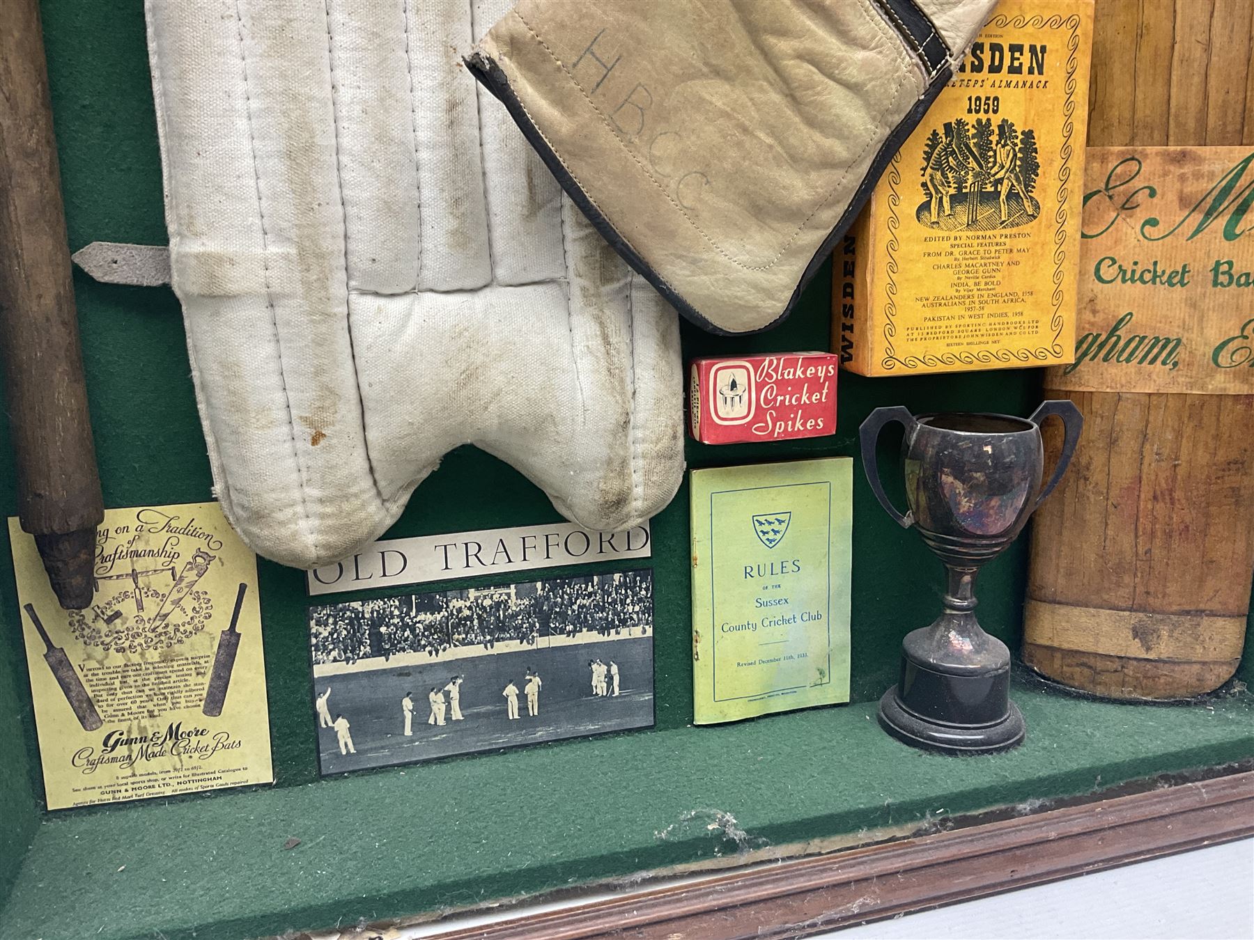 Four framed sporting memorabilia displays, the largest example containing 1930s cricket memorabilia, together with two fishing displays and a football display, each within wooden glazed frames, largest H105cm