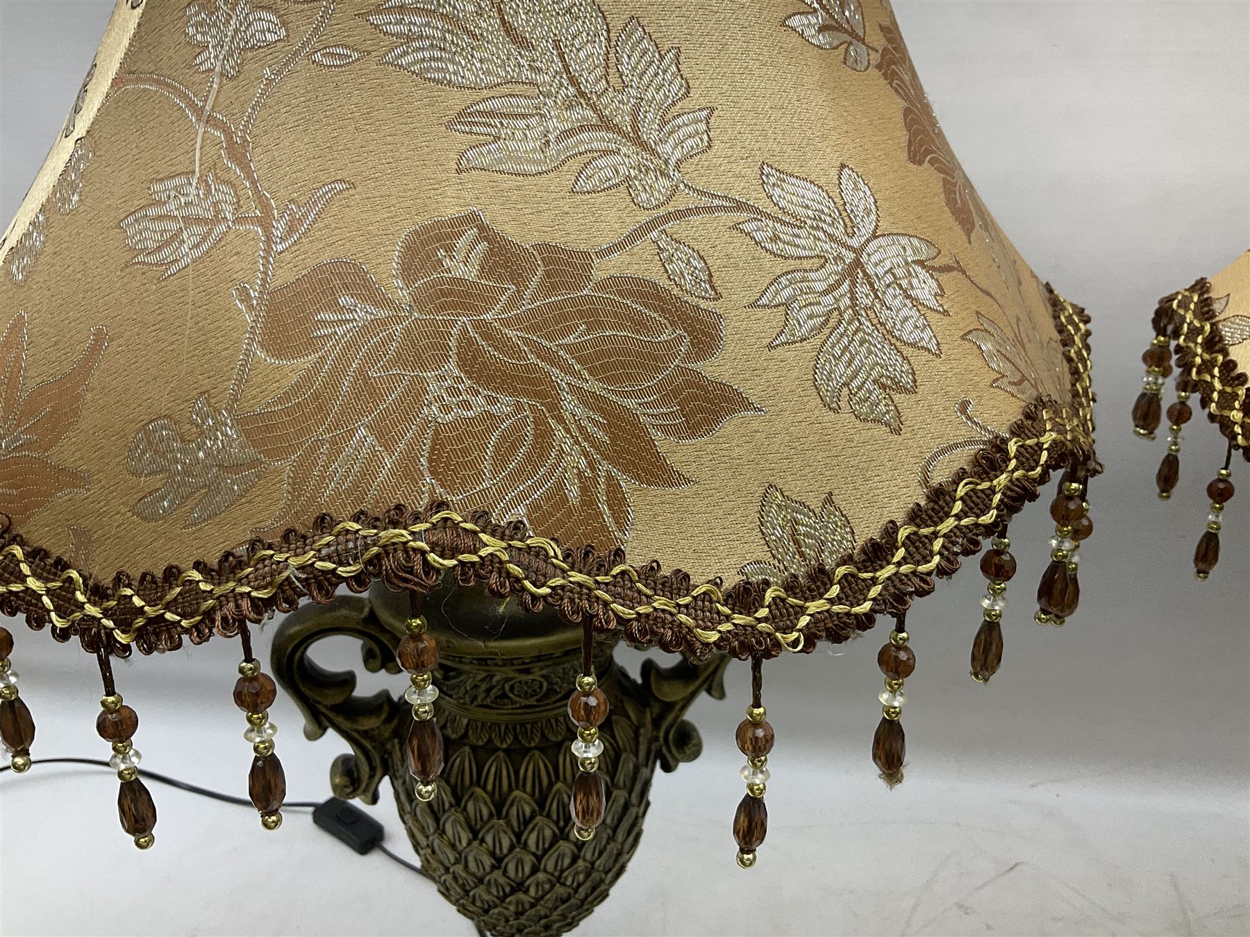 Pair bronzed amphora lamps with pineapple decoration, scroll handles and foliate base with scrolled feet together with pair peach ground shades and raised floral pattern H76cm (2)
