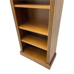 Georgian design walnut open bookcase, projecting cornice over figured banded frieze flanked by roundels, fitted with six adjustable shelves with flanking fluted uprights, on skirted base