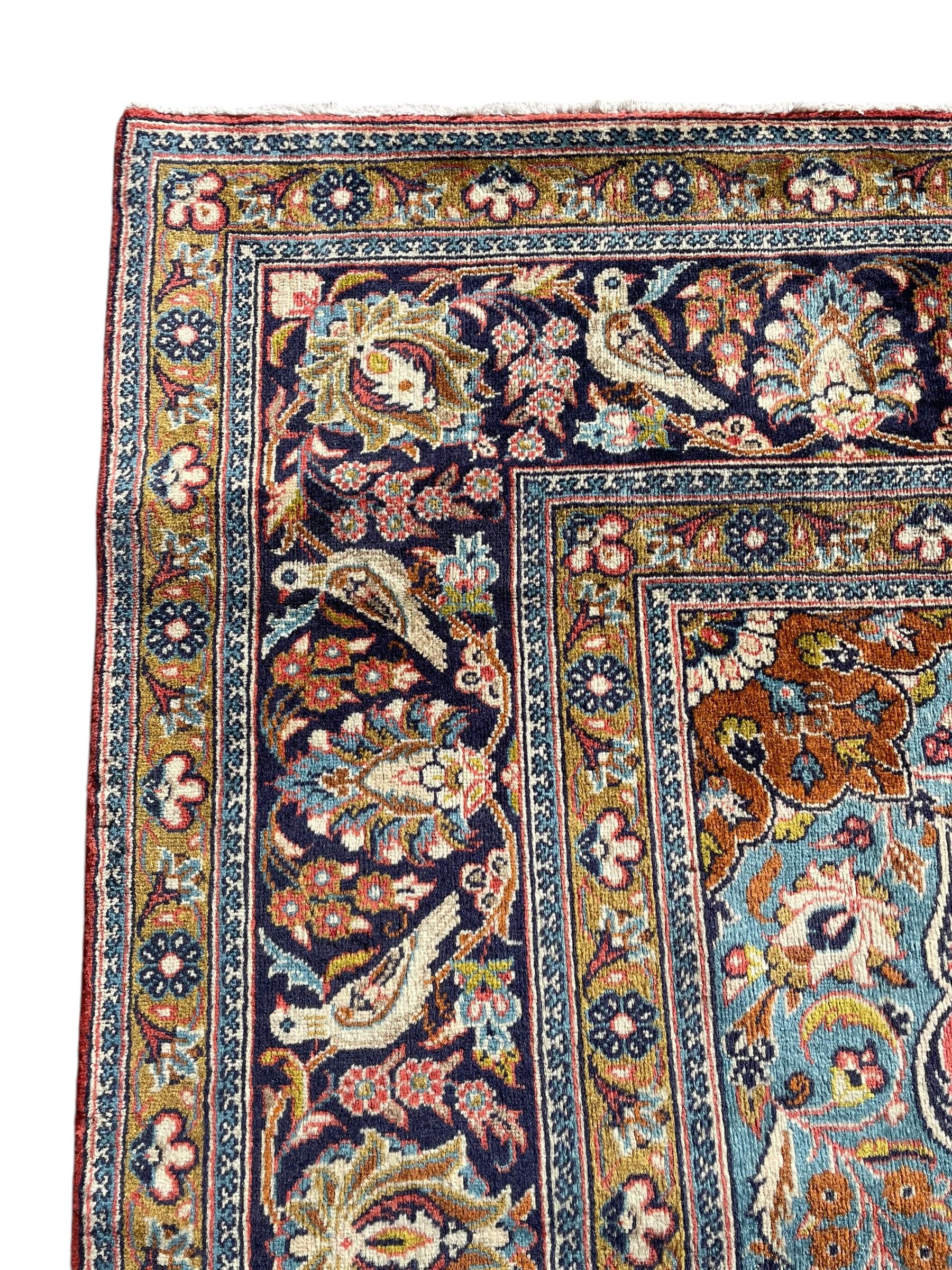 Persian Kashan peach ground rug, central rosette medallion surrounded by trailing branches and flower heads with bird motifs, light blue spandrels with further floral decoration, the main border with repeating palmettes and birds, within guard stripes