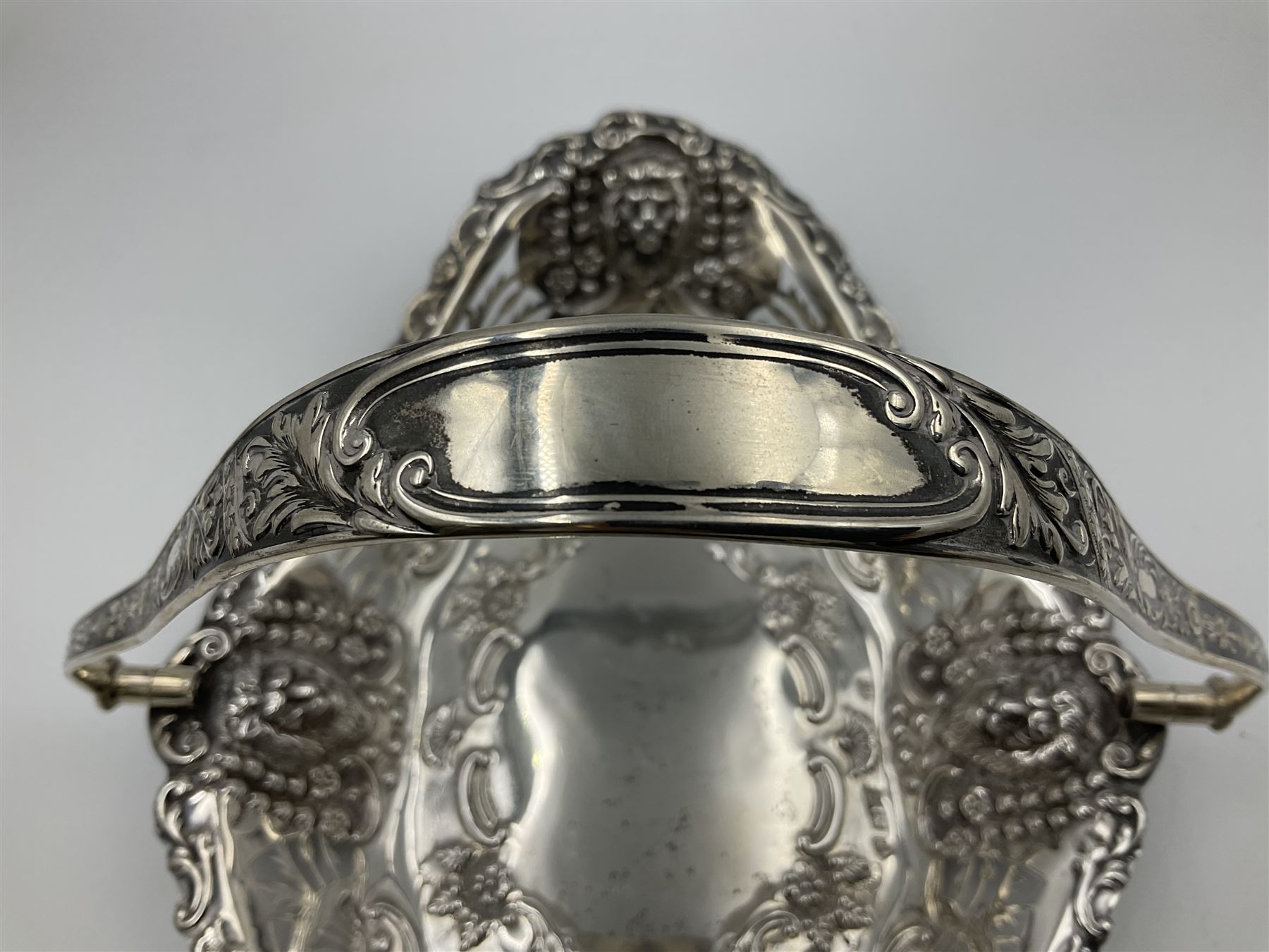 Edwardian silver swing handled basket, of navette form, with four repousse lion masks to each corner and with pierced and embossed floral, scroll and shell decoration to sides, base and handle, hallmarked Charles Horner, Birmingham 1906, height including handle H20cm