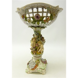  Late 19th century German Potschappel centrepiece, the base encrusted with fruit and flowers with pierced panels, the floral encrusted stem with applied with four cherubs supporting the pierced and hand painted bowl, H40cm   