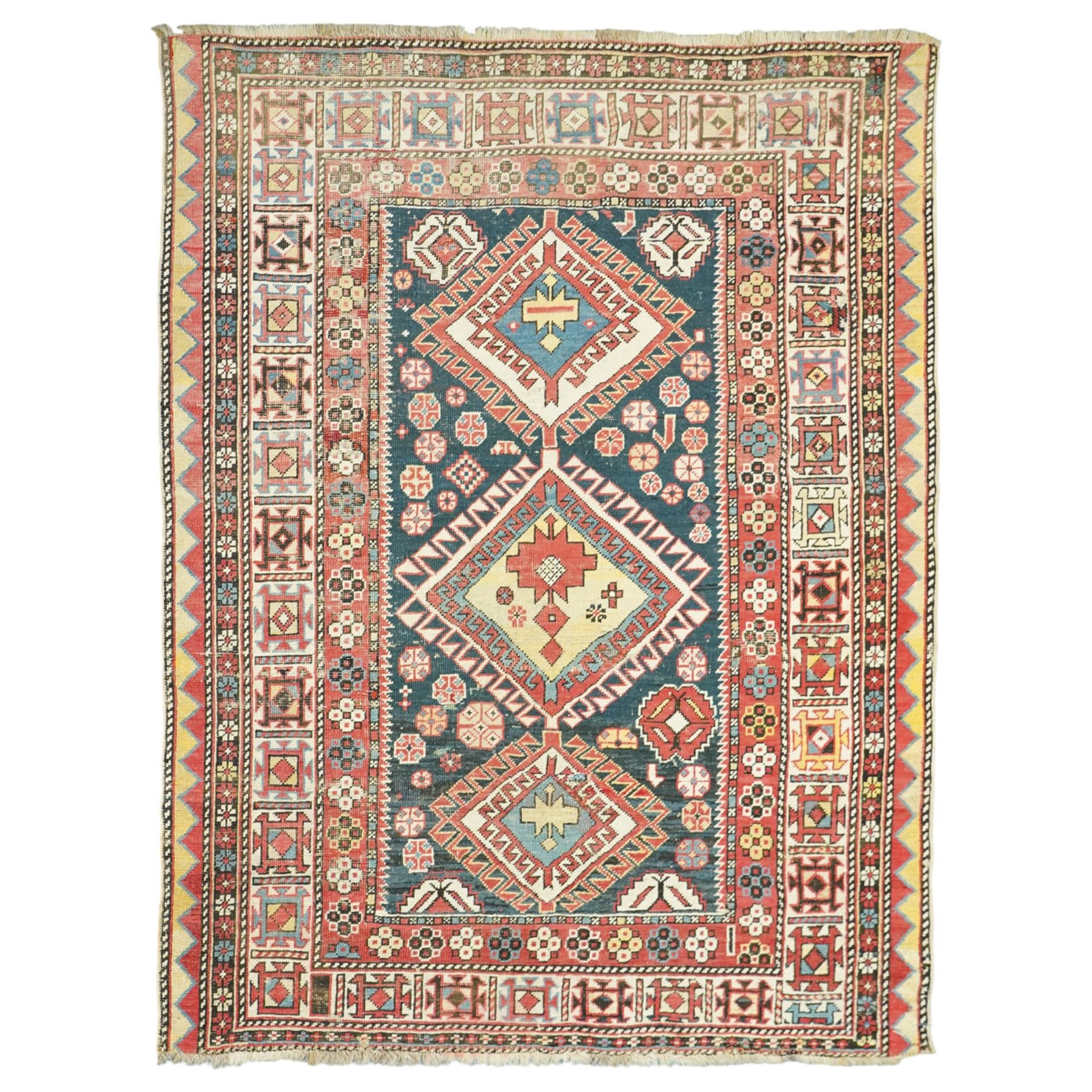 Vintage Caucasian Shirvan hand-knotted rug, indigo field with an arrangement of geometric diamond medallions and stylized tribal motifs within multiple patterned borders, with fringe ends 