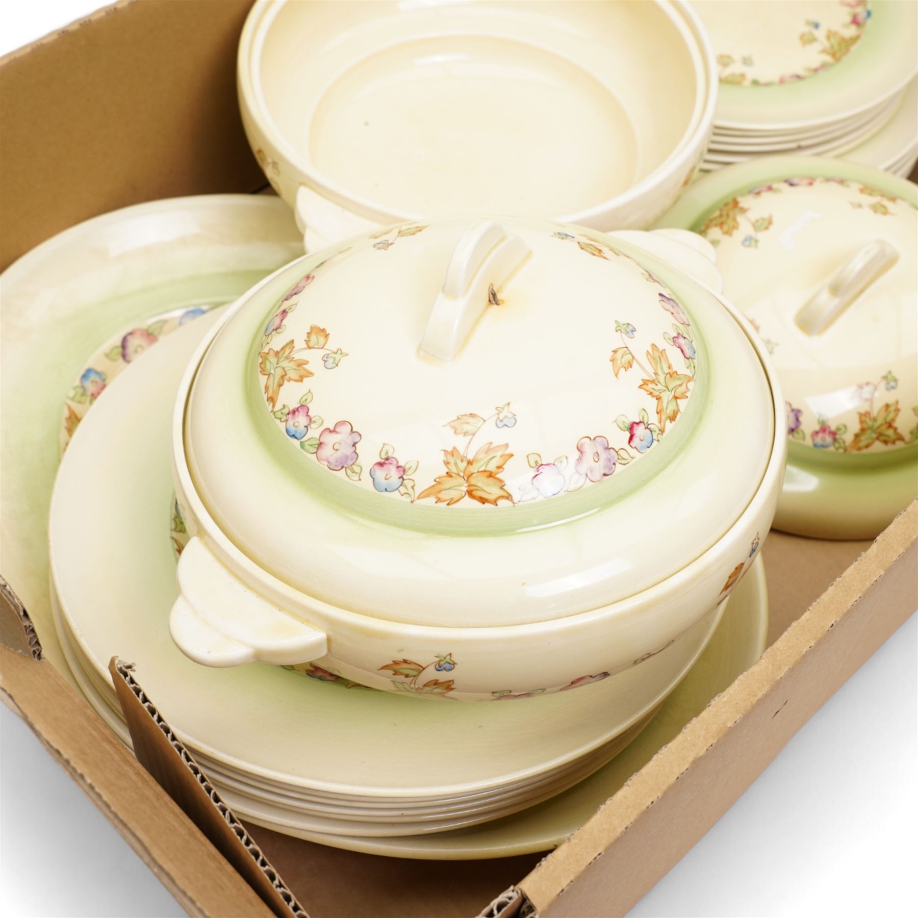 Clarice Cliff part dinner service, decorated with floral sprigs, including two covered tureens, six dinner plates, serving platter etc