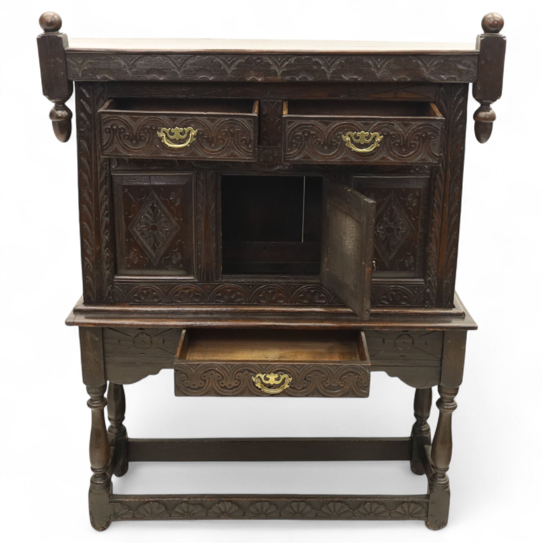 19th century and later carved oak court cupboard, the upper section with two drawers above a central cupboard door flanked by panels, lower section with single long drawer, on turned supports united by carved stretchers