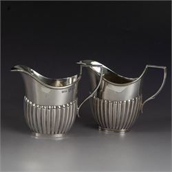 Victorian silver two piece bachelors tea service, comprising teapot and milk jug, of oval part fluted form, the teapot with ebonised wooden handle and finial, hallmarked Josiah Williams & Co, London 1895, together with a silver milk jug and open sucrier, of similar form, hallmarked William Hutton & Sons, London 1898