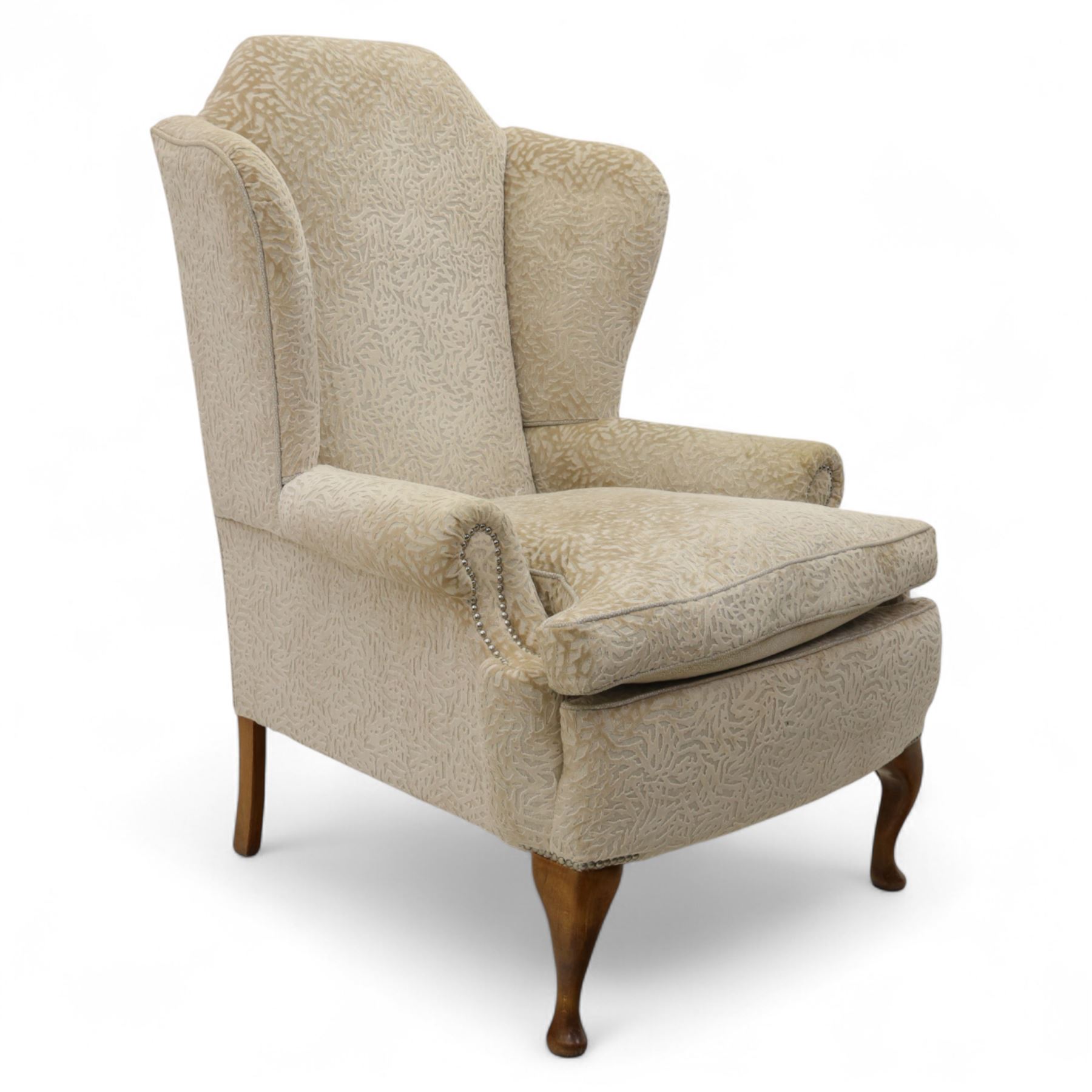 Late 20th century wingback armchair, upholstered in beige embossed fabric with brass stud edging, on cabriole legs and splayed rear legs