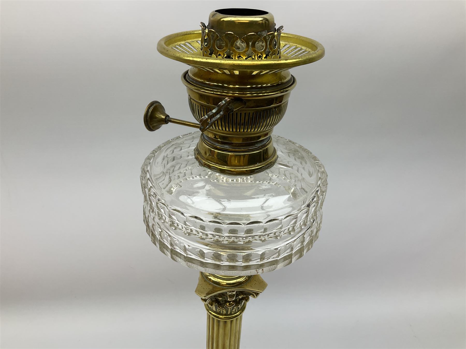 Victorian brass oil lamp, the square stepped base leading to a Corinthian column supporting a part slice cut clear glass reservoir, burner, clear glass chimney and foliate etched glass shade with amber rim, overall H80cm