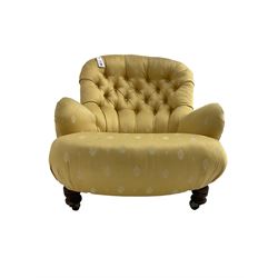 Victorian spoon back low armchair, upholstered in yellow buttoned fabric with sprung seat, raised on turned feet with castors