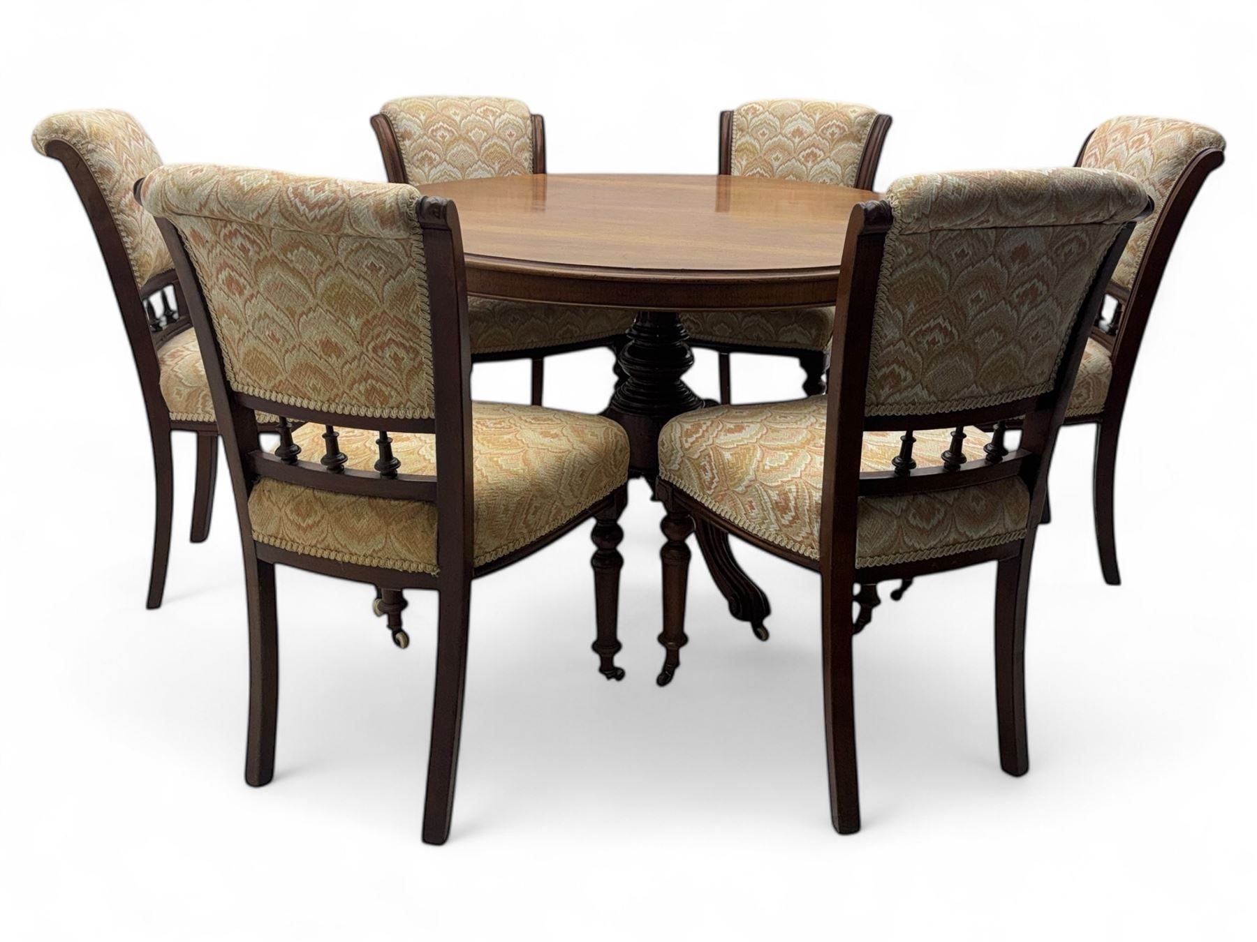 Victorian mahogany centre table, circular top above turned pedestal, terminating on three cabriole legs with scroll feet on porcelain castors, and six scroll carved upholstered dining chairs, with cushion and spindle turned backs, centre table  118x74cm, dining chairs 89x46x50cm