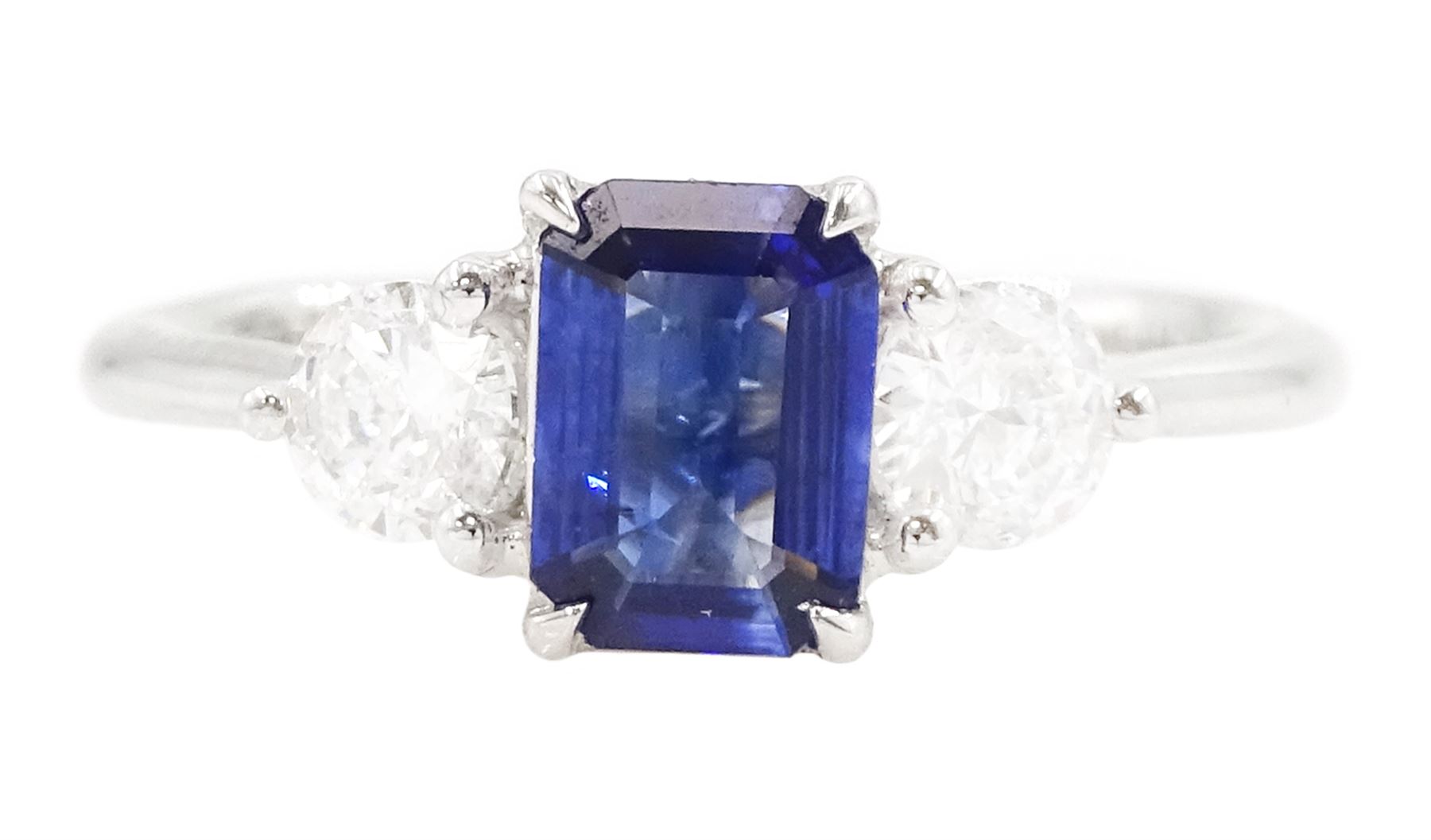 Platinum sapphire and diamond three stone ring, single emerald cut sapphire of approx 0.70 carat, either side set with two round brilliant cut diamonds, hallmarked, total diamond weight approx 0.50 carat
