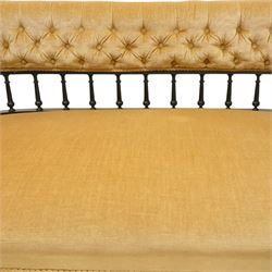 Late Victorian Aesthetic Movement settee, with buttoned upholstered roll-over back and arms, open spindle gallery frame with turned uprights, stuff-over seat, on shaped ebonised supports