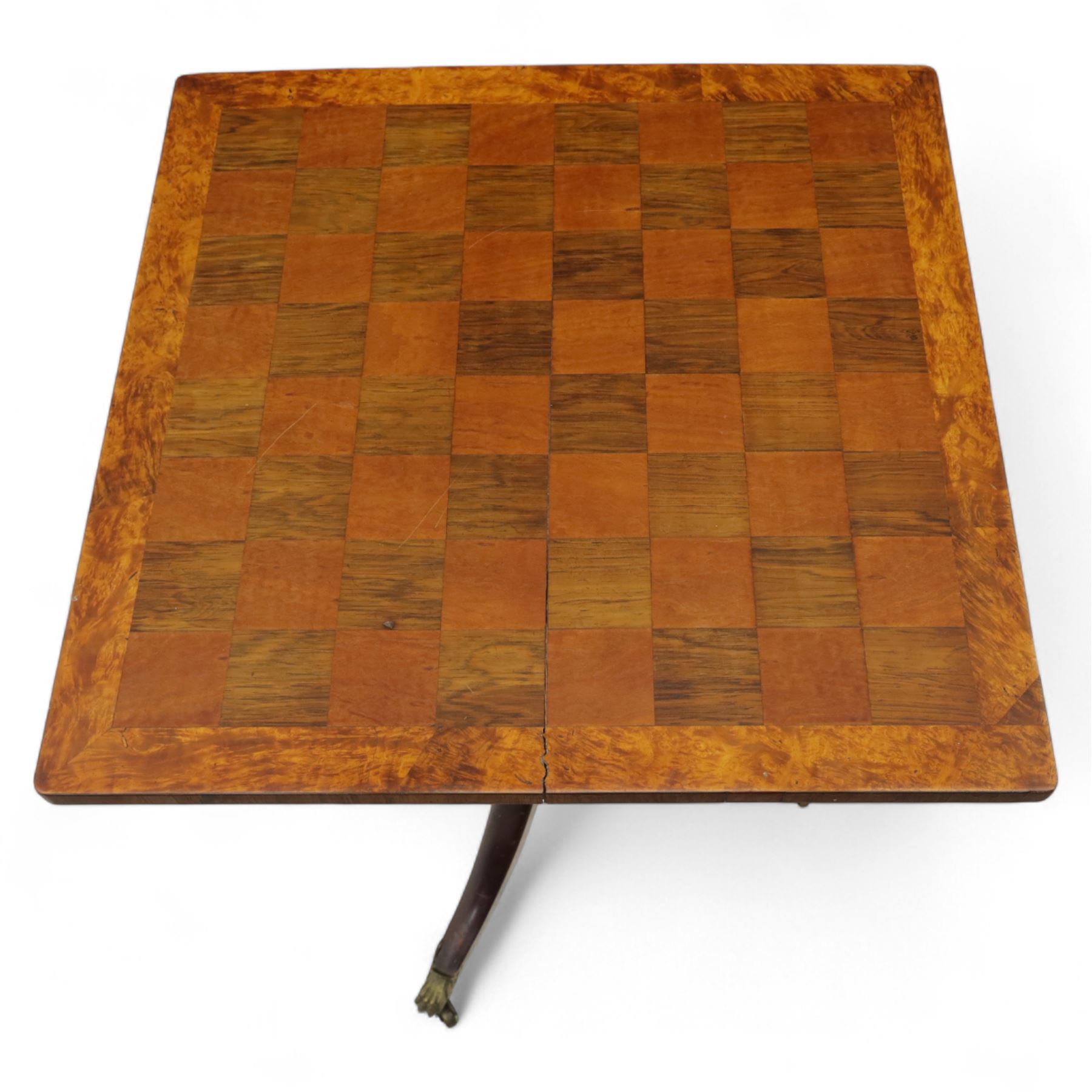 Early 20th century walnut chess table, square checkered veneered top with crossbanded edge, raise on a turned column based with acanthus craving, on three outswept legs terminating in brass paw caps above castors