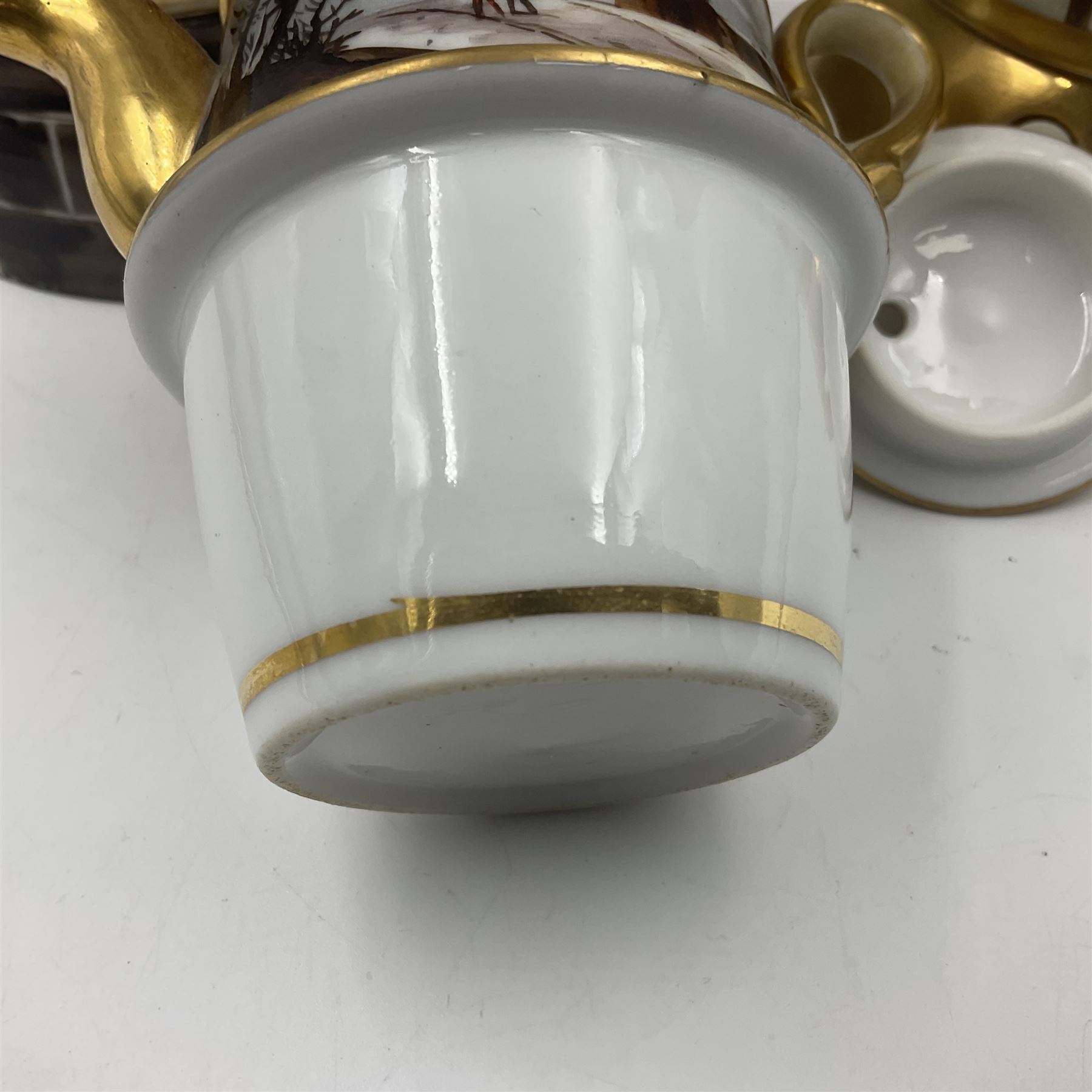 Two 19th century continental teapots and warmers, each teapot upon a cylindrical warming base in the form of a castle, hand printed with winter landscapes, largest H22cm 