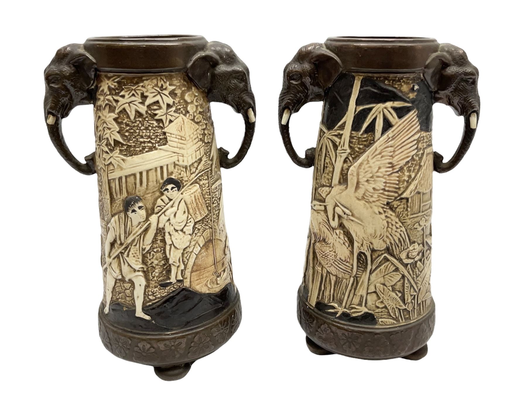 Pair of Bretby vases of tapering cylindrical form decorated with elephants, cranes and fishermen, the bodies with twin elephant mask handles, with coppered borders, raised upon three bun feet, stamped Bretby 2246 marks beneath, H32cm