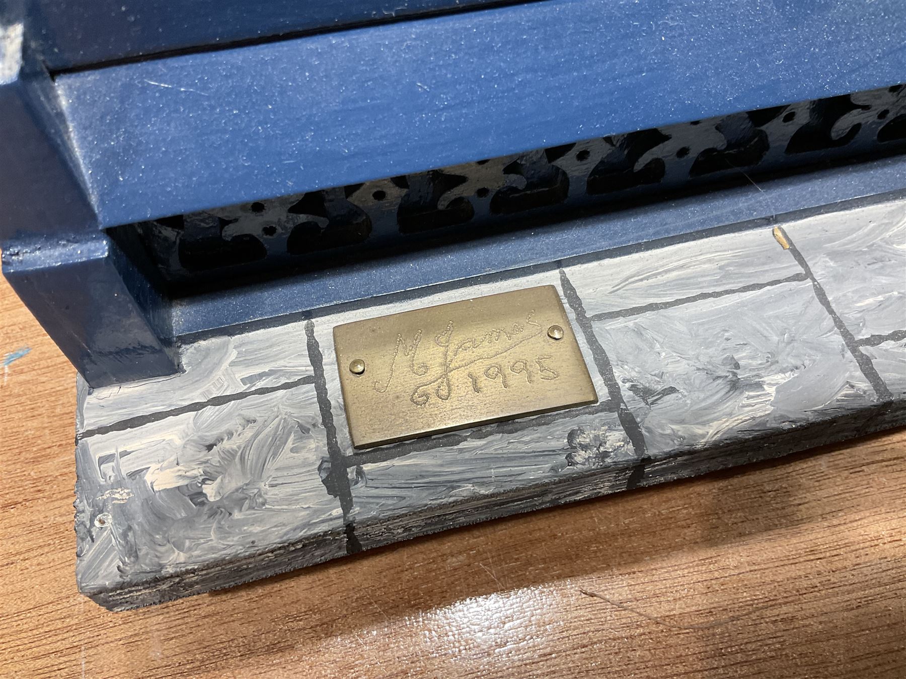 Good quality late 20th century dolls house by M. James dated 1995 in the form of a Beverley East Yorkshire Antique Shop called 'North Bar Antiques'; single-storey single-roomed shop with textured brick walls and flat roof, fully glazed hinged front with recessed hinged customer door and central window to the rear; comprehensively furnished with chests of drawers, pedestal desk, breakfast table, lowboy, two longcase clocks, delft rack with ceramics, occasional tables, pictures, Regency style mirror and collectibles; decorated walls with coving and picture rail and simulated floorboarding; wired for electric lighting; maker's plaque W61cm H42.5cm D41.5cm