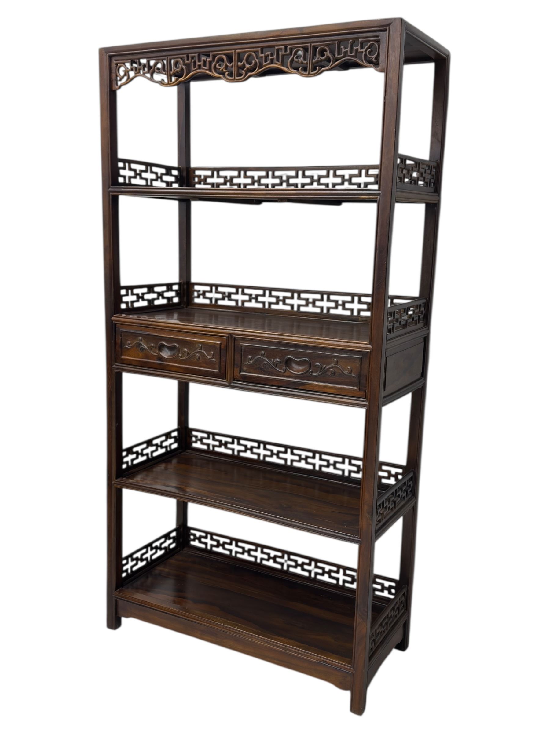 Early 20th century Chinese hardwood display étagère bookcase, the rectangular open tiered frame with pierced frieze and geometric openwork gallery to each shelf, fitted with two short drawers carved with stylised lotus motifs, supported on square uprights with pierced apron and integral gallery rails