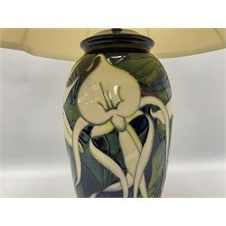 Moorcroft table lamp of baluster form, decorated with white flowers amongst foliage on merging dark blue and cream ground, raised upon circular spreading base, with original label and gilt stamp to the felt lined base, H29cm excl fitting
