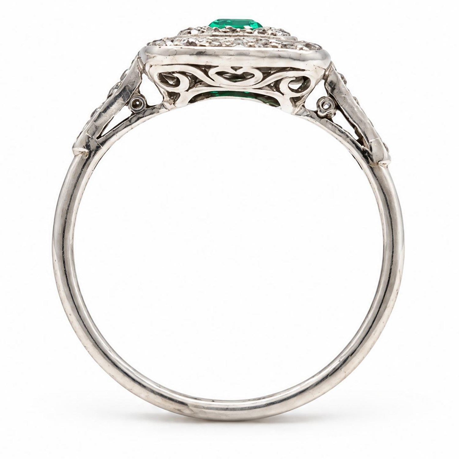 Early 20th century palladium emerald and diamond halo cluster ring, single rectangular cut emerald of approx 0.30 carat, surrounded by two rows of milgrain set diamonds and diamond set shoulders