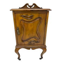 Edwardian Art Nouveau walnut bedside cabinet, raised broken swan neck back with carved flower heads, single fielded panelled door enclosing single shelf, raised on cabriole supports with ceramic castors
