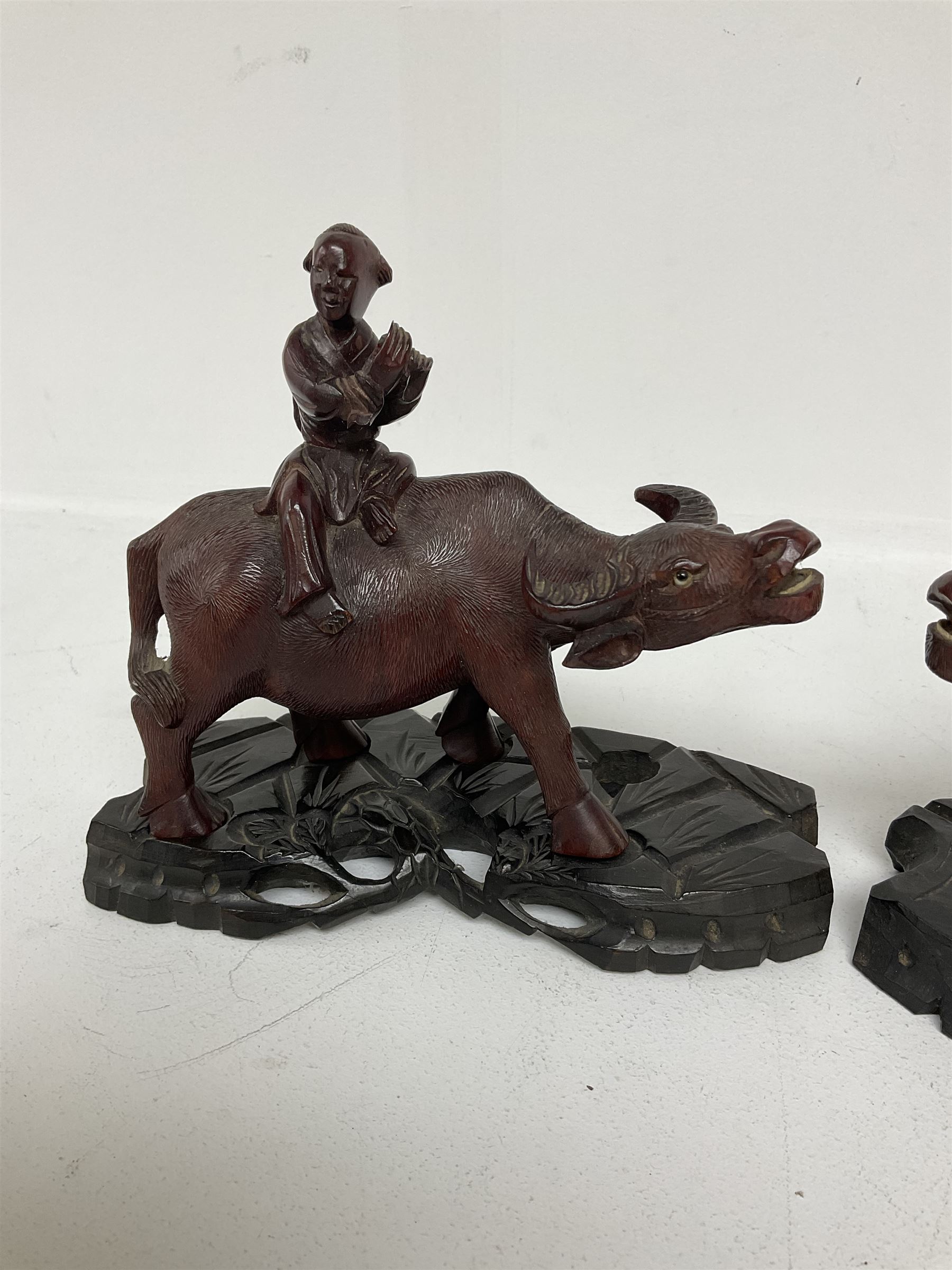 Pair of Chinese hardwood figures of farmers riding water buffalo, on stands, H19cm