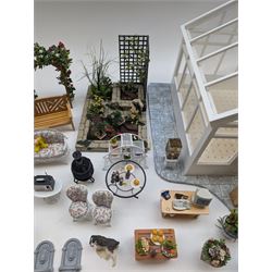 1:12 scale dolls house conservatory and garden accessories, including white wooden glazed conservatory on a stone effect base, black and white metal garden seating, barbecue, plant shelves, parasol, barbeque accessories, large planters, rabbit hutch, animals, chimenea, etc